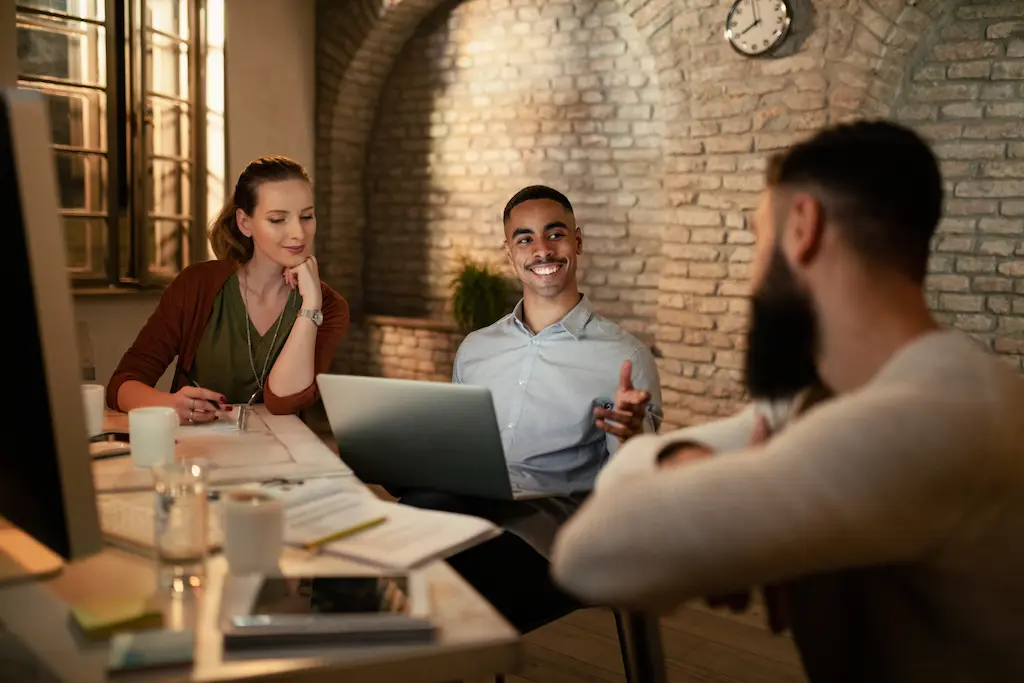 happy-african-american-businessman-communicating-with-his-coworkers-while-using-laptop-meeting